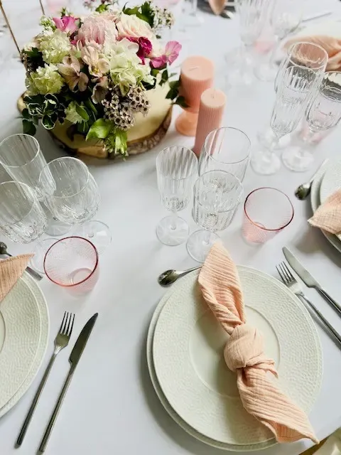 Table dressée avec des assiettes, des verres, des couverts, des bougies et un centre de table floral