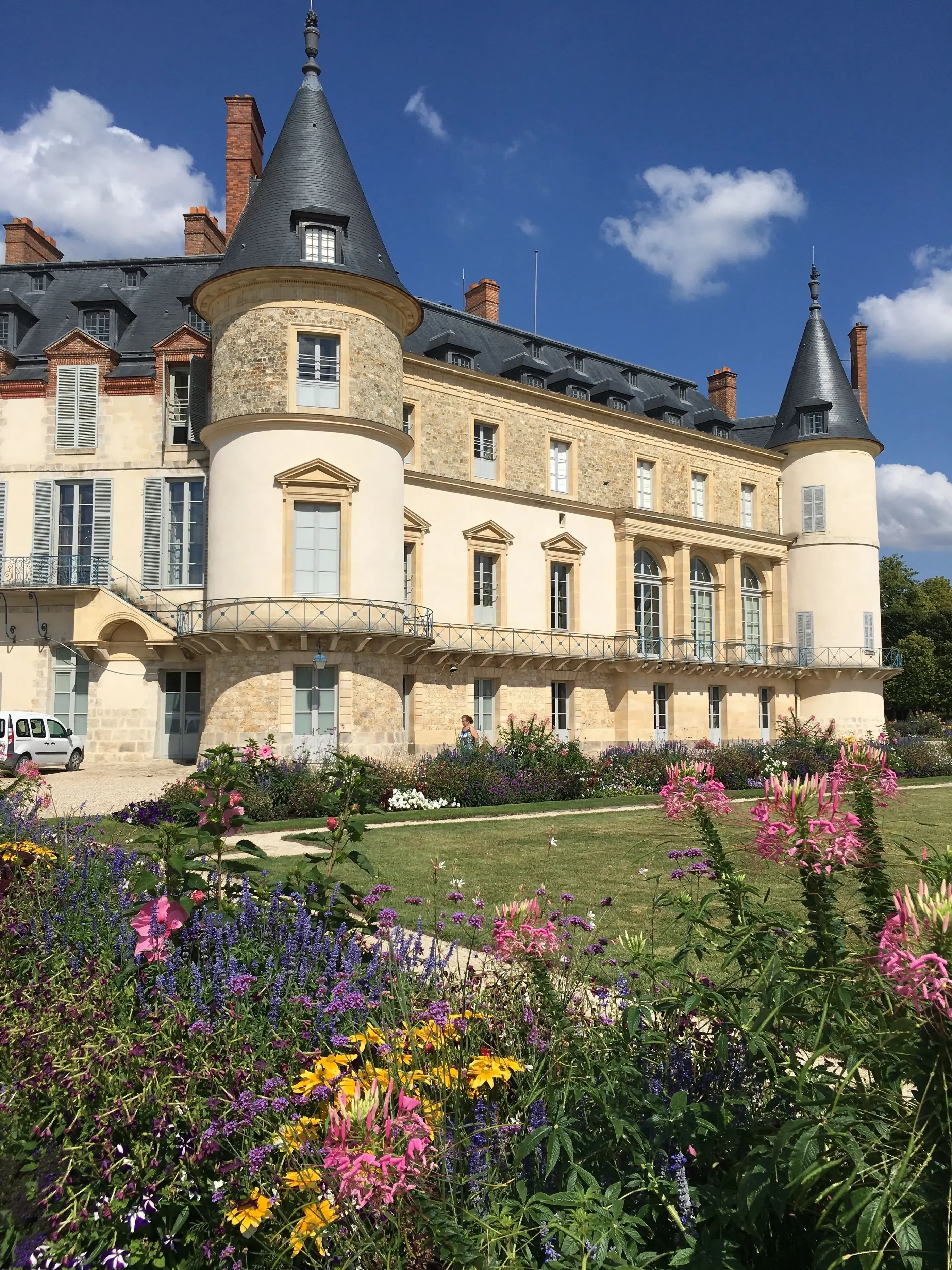 Château avec tours coniques et jardin fleuri devant un ciel bleu