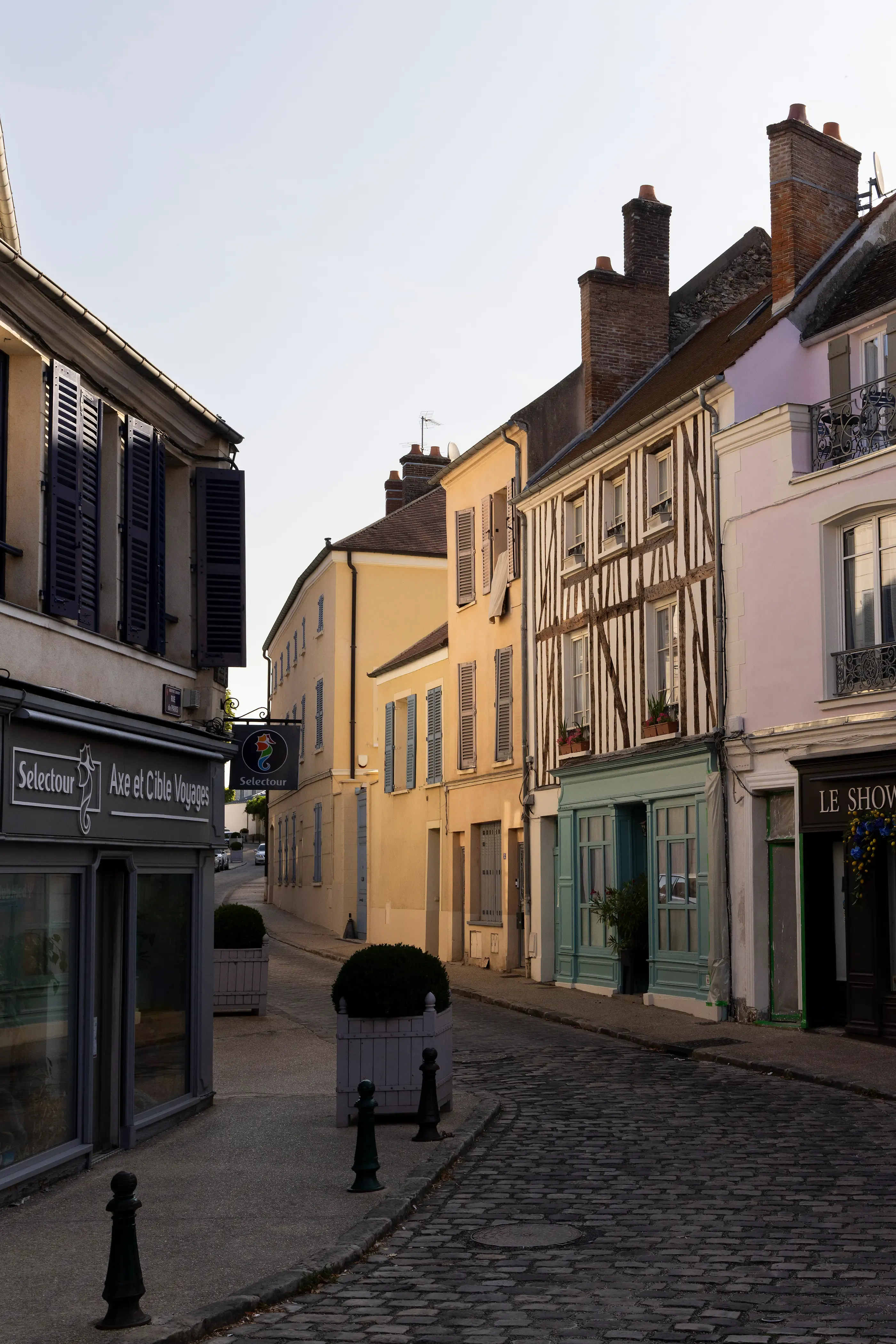 Rue pavée bordée de bâtiments anciens avec boutiques et maisons à colombages