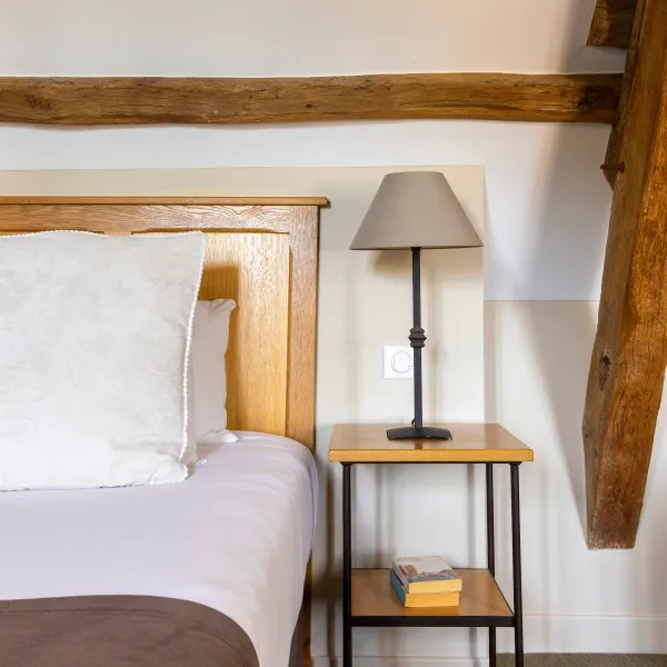 Lit avec une tête de lit en bois, une lampe de chevet et une table de nuit avec des livres