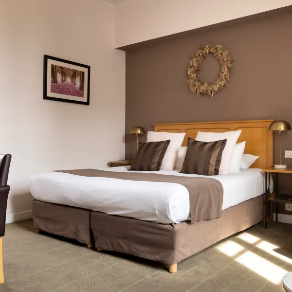 Chambre avec un lit double, une table de chevet, une chaise et une table près de la fenêtre, un miroir et une décoration murale